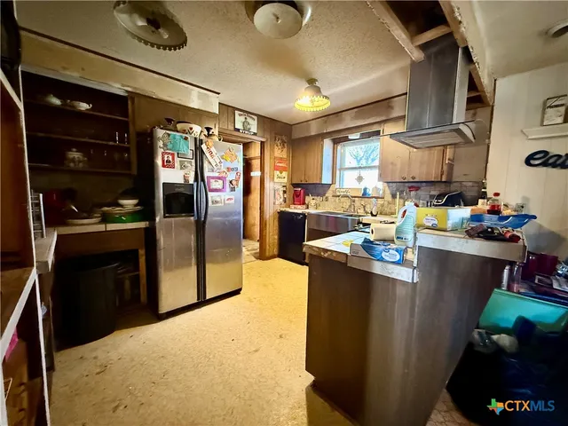 a kitchen with stainless steel appliances granite countertop a refrigerator a stove and a sink