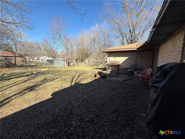 a view of a backyard with table and chairs under an umbrella