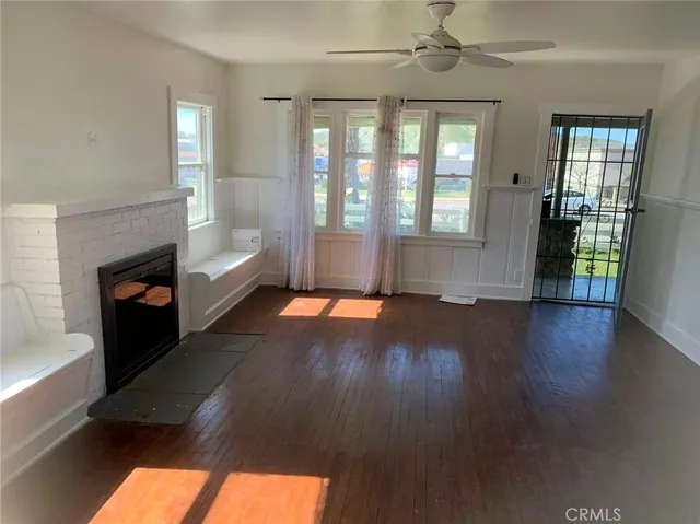 wooden floor in an empty room with a fireplace and a window