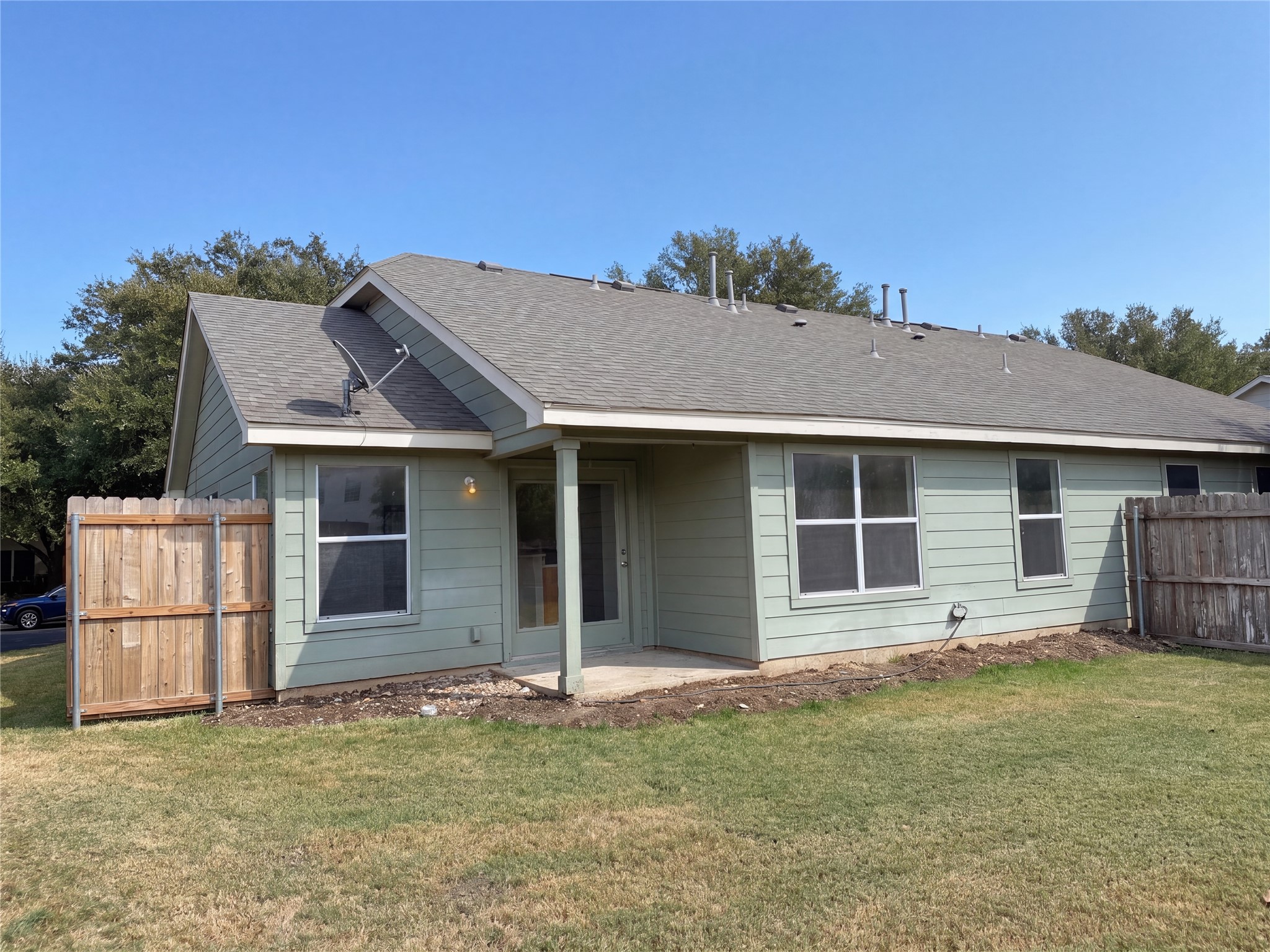 A covered back patio overlooks the grassy yard surrounded by wooden privacy fencing.