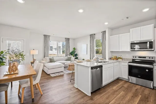 a kitchen with white cabinets and wooden floor