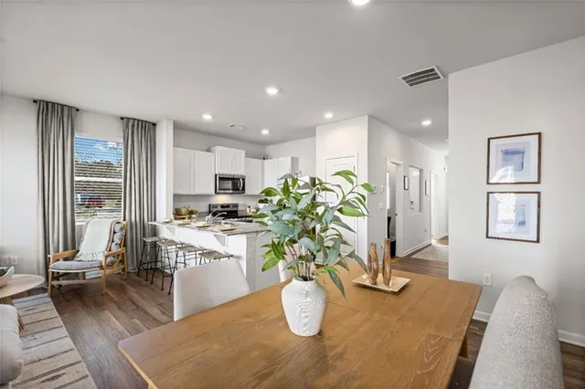 a living room with stainless steel appliances furniture dining table and wooden floor