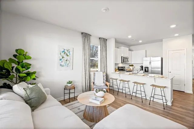 a living room with stainless steel appliances furniture a dining table and chairs