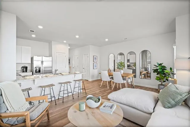 a living room with furniture kitchen view and large windows