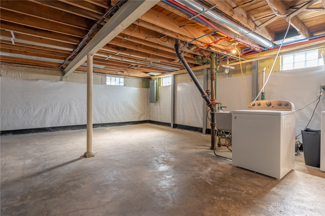 326 North Bromfield Road Kettering, OH 45429 - Photo 23 of 30 This utilitarian basement offers practical space with exposed joists and essential laundry facilities.