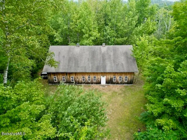 an aerial view of a house with yard and trees in the background