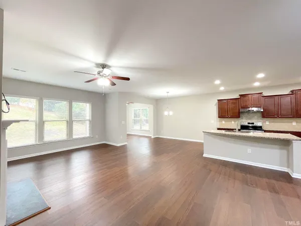 an empty room with wooden floor and ceiling fan