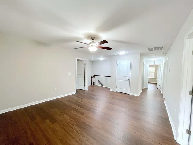 a view of a room with wooden floor and a ceiling fan
