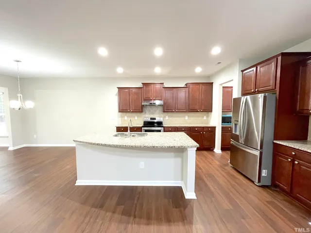 a large kitchen with stainless steel appliances granite countertop plenty wooden cabinets counter space a sink and a fireplace