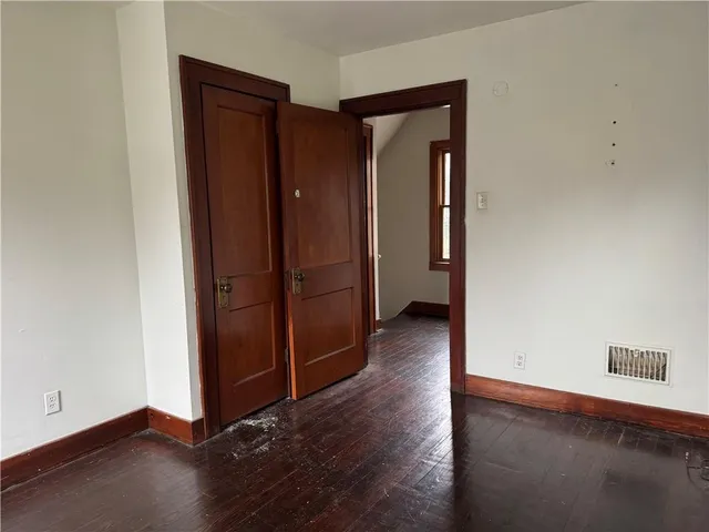 an empty room with wooden floor and closet