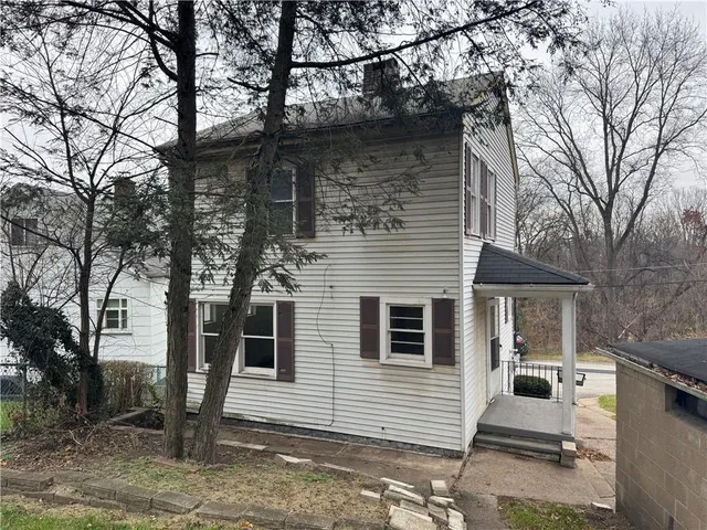 a view of a white house with a large tree