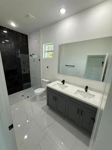 a spacious bathroom with a double vanity sink toilet and shower