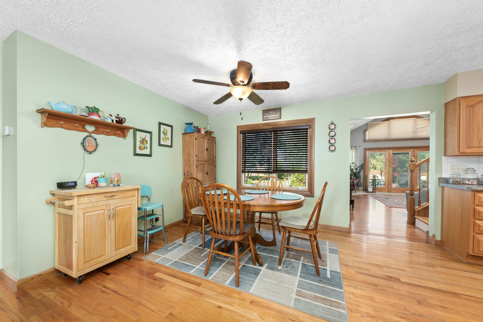 26310 South McKinley Woods Road Channahon, IL 60410 - Photo 6 of 49 a dining room with wooden floor a chandelier fan a wooden table and chairs