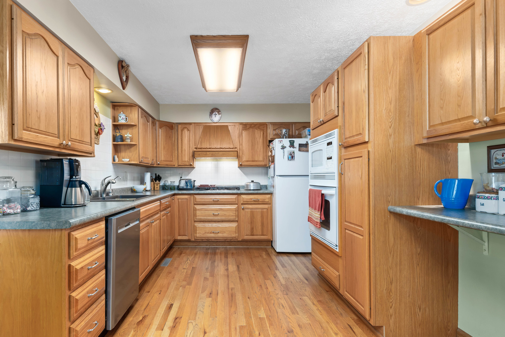 26310 South McKinley Woods Road Channahon, IL 60410 - Photo 9 of 49 a kitchen with stainless steel appliances granite countertop a refrigerator a sink dishwasher a stove and white countertops with wooden floor