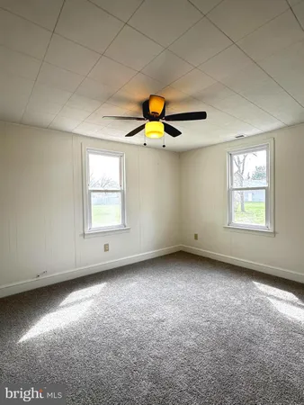 an empty room with windows and ceiling fan