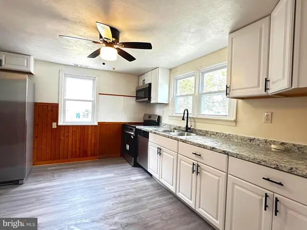 a kitchen with granite countertop a refrigerator a sink and dishwasher with wooden floor