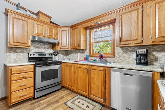 a kitchen with stainless steel appliances granite countertop a stove a sink and a microwave
