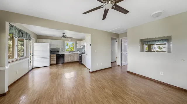 a kitchen with stainless steel appliances wooden floors and white cabinets