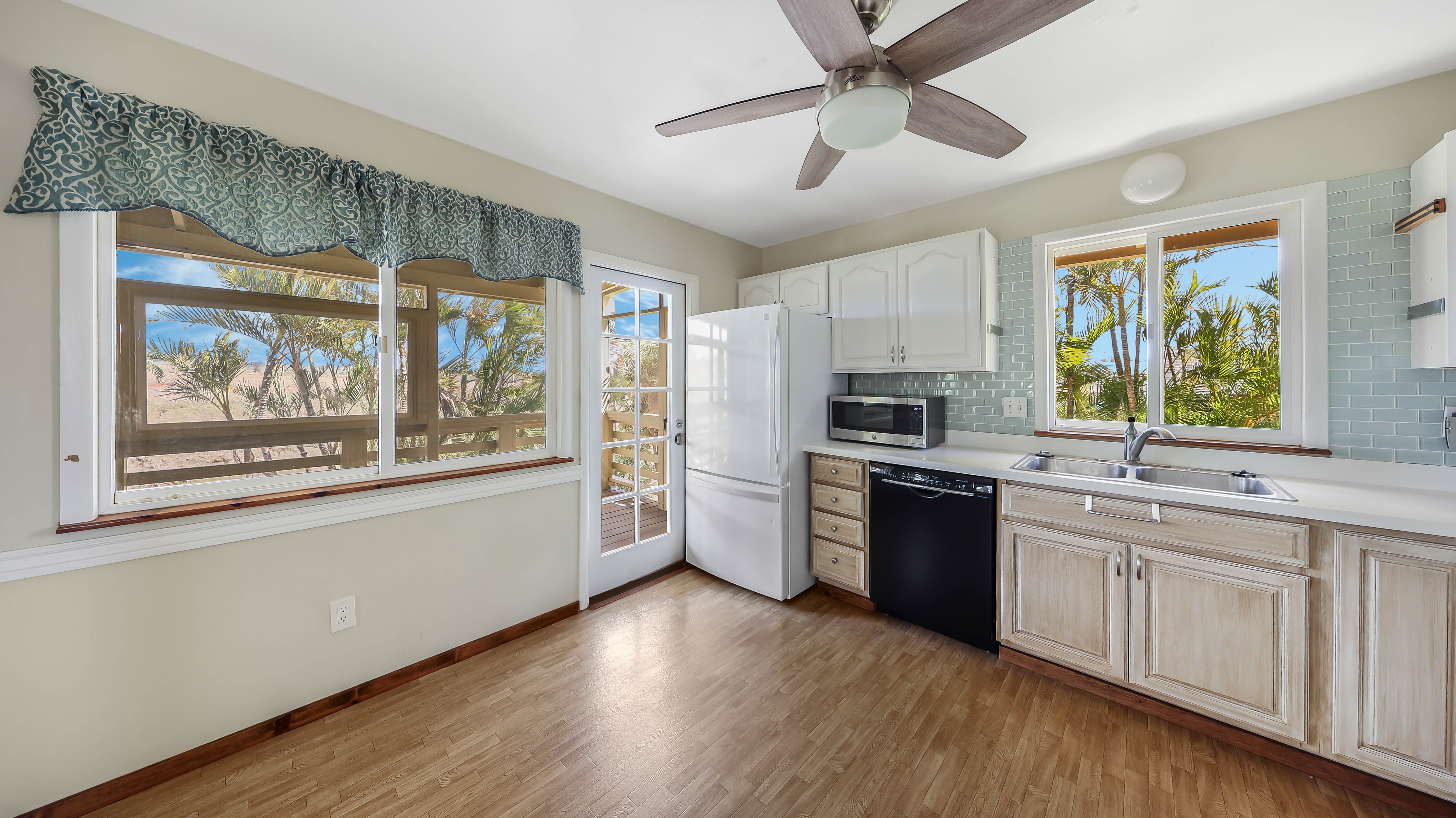 5060 Alii Road Hanapepe, HI 96716 - Photo 12 of 30 a kitchen with stainless steel appliances wooden floors and white cabinets