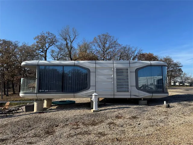 a view of a small house with a yard and wooden fence