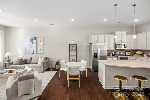 a living room with stainless steel appliances kitchen island granite countertop furniture and wooden floor