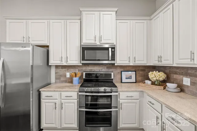 a kitchen with stainless steel appliances white cabinets and a stove a refrigerator with wooden floor