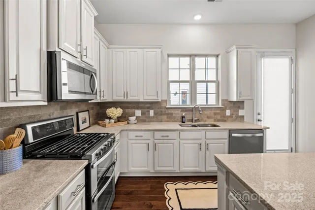 a kitchen with stainless steel appliances granite countertop a stove a sink and a microwave