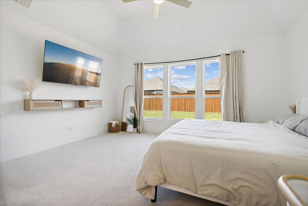 1710 Highwood Road Forney, TX 75126 - Photo 11 of 25 Spacious room featuring vaulted ceilings, light-toned carpeting, a built-in floating media console, and a triple window overlooking a fenced yard