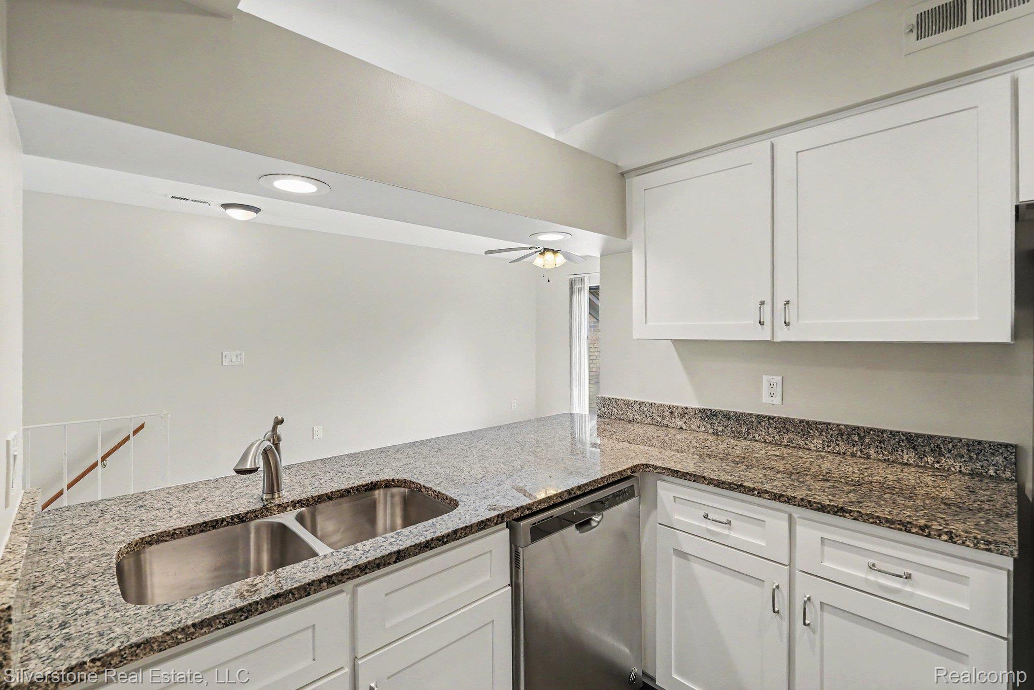 1502 Meadowside Drive Rochester, MI 48307 - Photo 12 of 27 Kitchen featuring granite countertops, a double basin stainless steel sink with a gooseneck faucet, white shaker-style cabinetry, and a built-in dishwasher