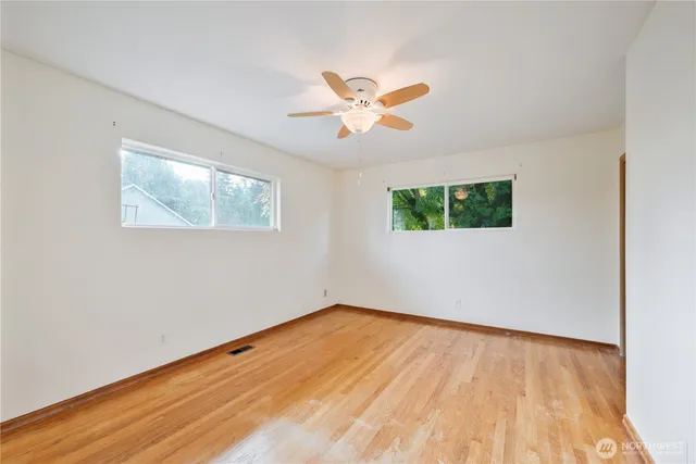 a view of empty room with wooden floor and fan
