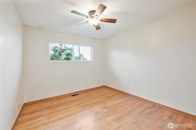 an empty room with windows and fan