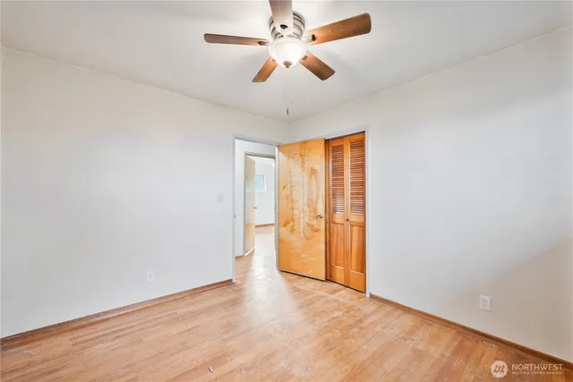 an empty room with closet and a ceiling fan