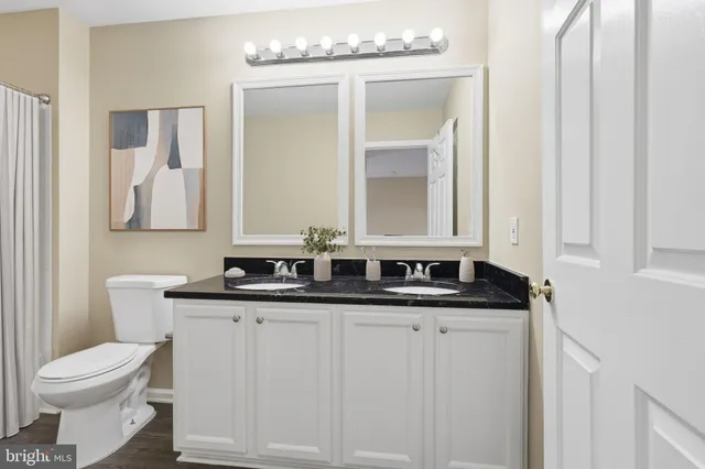 a bathroom with a granite countertop sink a toilet and mirror