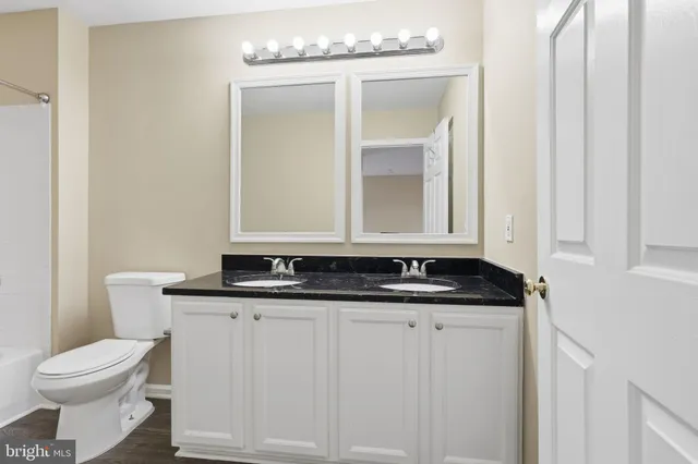 a bathroom with a granite countertop toilet a sink and a mirror