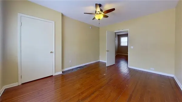 an empty room with wooden floor and chandelier fan