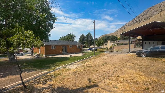 120 North 1230 E Street Springville, UT 84663 - Photo 38 of 60 Brick exterior with a dark shingle roof and a spacious backyard featuring mature trees