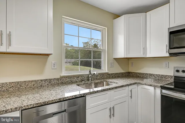 a kitchen with granite countertop white cabinets and a sink