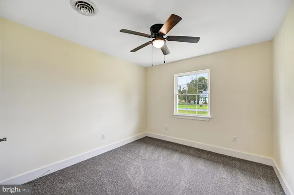a view of a big room with a ceiling fan and windows