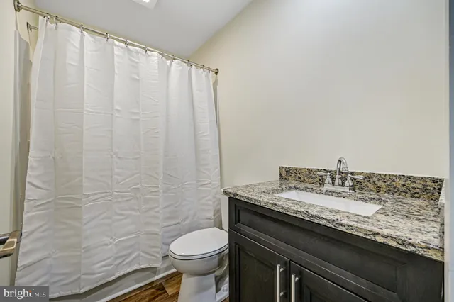 a bathroom with a granite countertop sink and a toilet