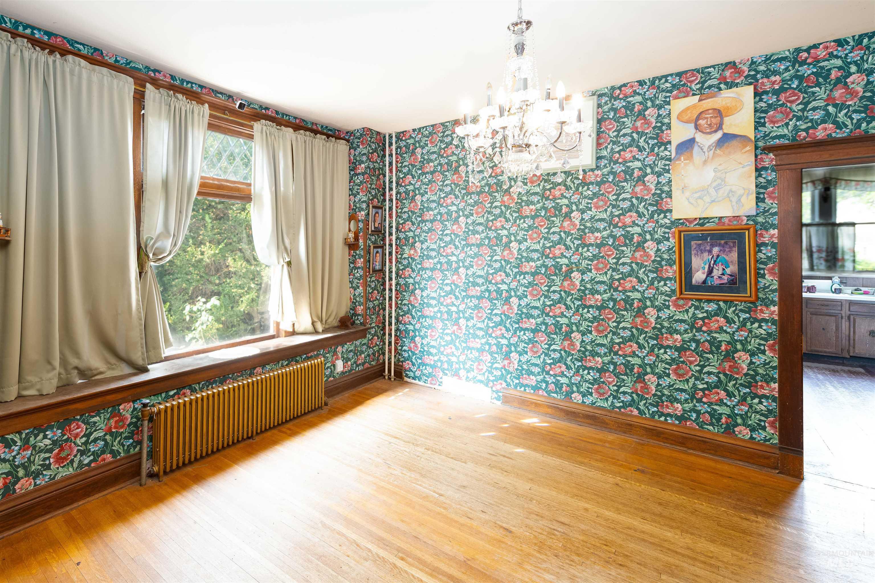 507 7th Avenue Lewiston, ID 83501 - Photo 15 of 30 Unfurnished room featuring wallpapered walls, light wood-type flooring, radiator heating unit, and a chandelier
