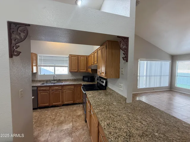 a large kitchen with granite countertop a sink and a stove