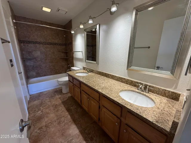 a bathroom with a granite countertop sink a mirror a bathtub and shower