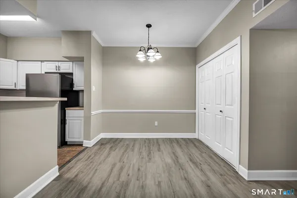 a view of a room with wooden floor a ceiling fan and a kitchen