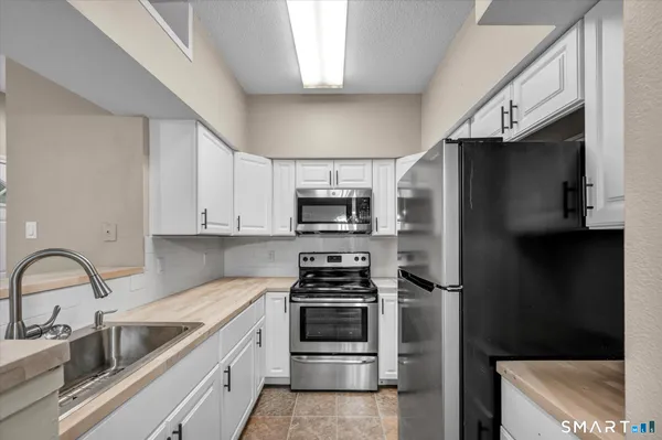 a kitchen with stainless steel appliances a refrigerator a sink and white cabinets