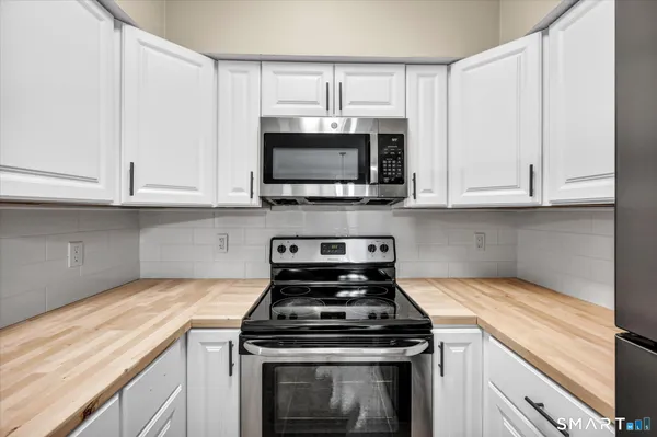 a kitchen with granite countertop a stove top oven microwave and cabinets