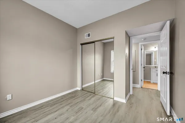 a view of an empty room with wooden floor and a bathroom