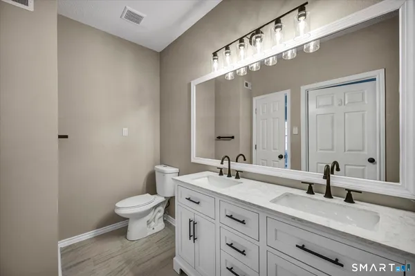 a bathroom with double vanity sinks a toilet a mirror and vanity