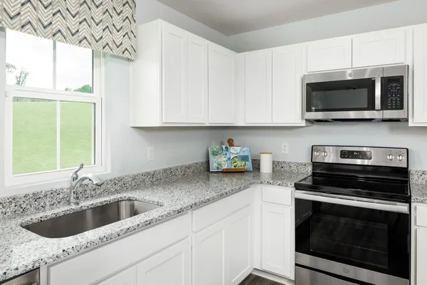 a kitchen with stainless steel appliances granite countertop a sink a stove a microwave and cabinets