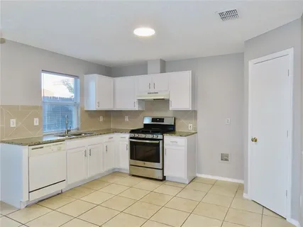 a kitchen with granite countertop white cabinets and appliances