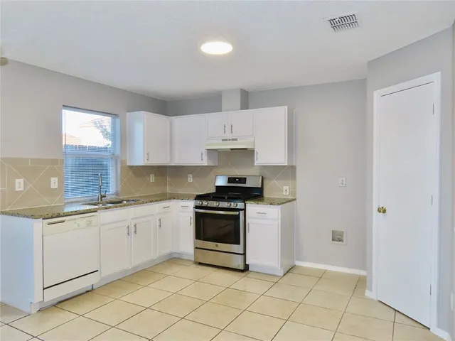 a kitchen with granite countertop white cabinets and appliances